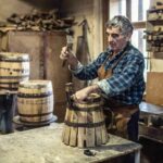 aged man crafts a new vintage looking wooden barrel using