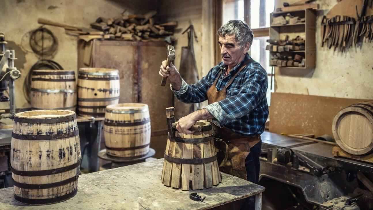 aged man crafts a new vintage looking wooden barrel using